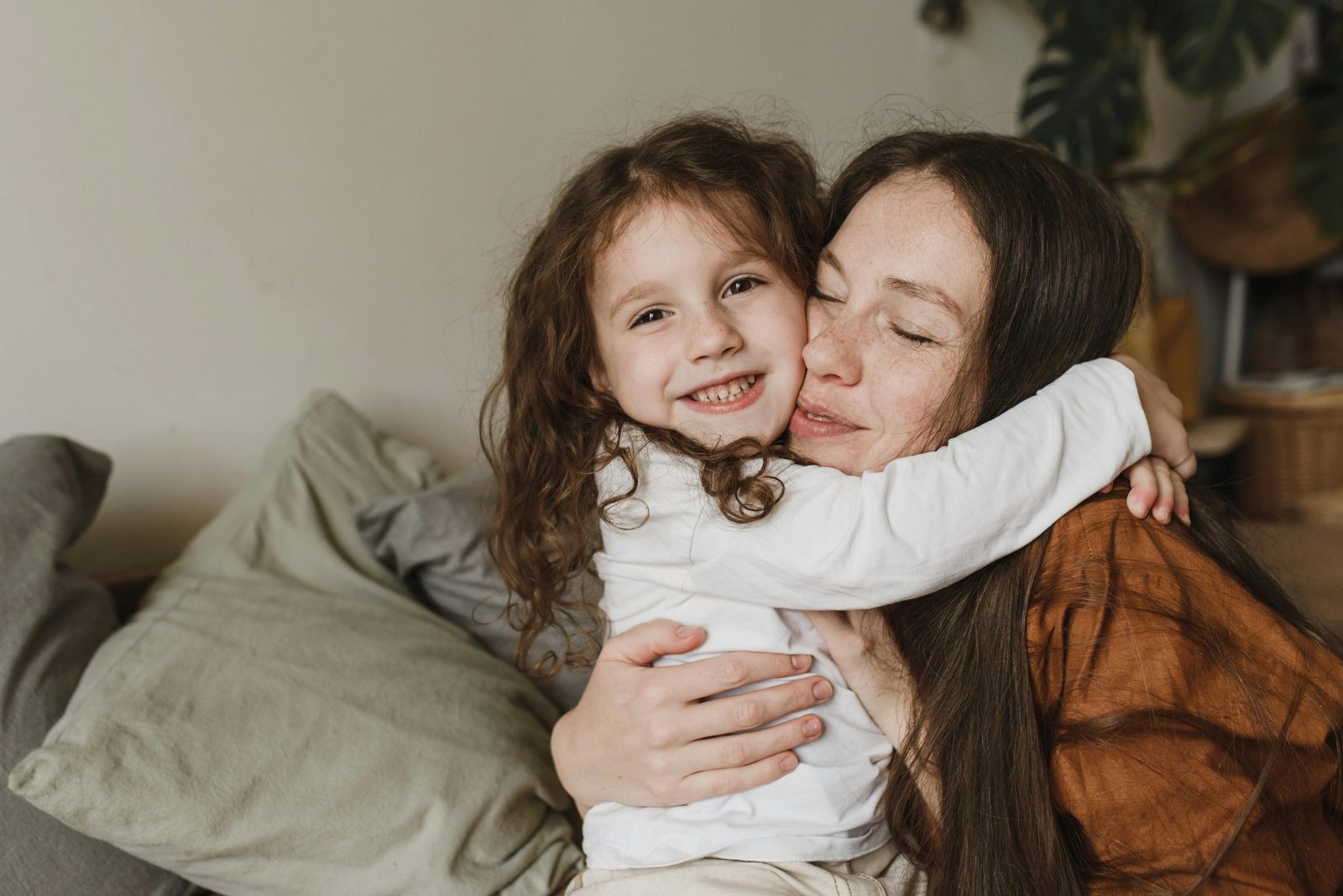 A mother holding her smiling young daughter close.